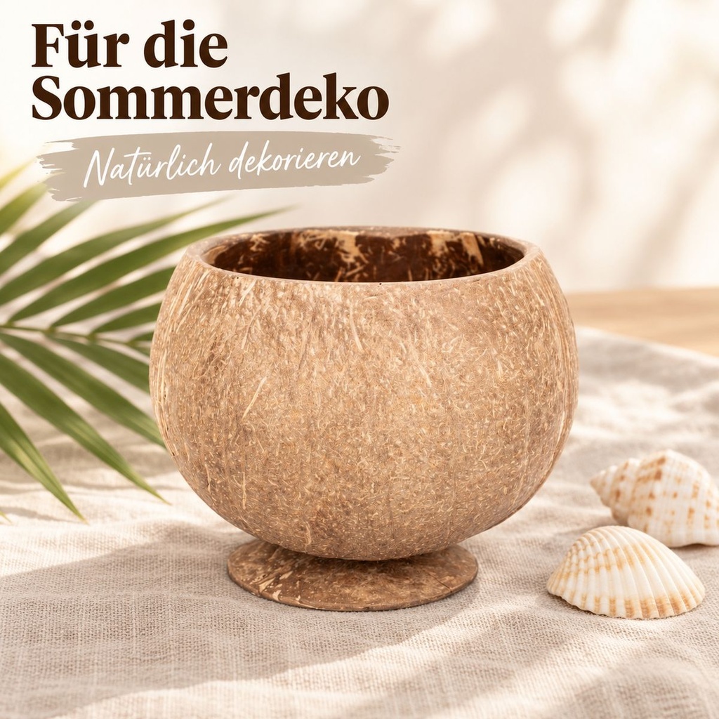 Becher aus echter Kokosnussschale mit angesetztem Standfuß auf dem sommerlich gedeckten Tisch neben Palmenblatt und Muscheln