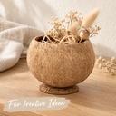 Becher aus echter Kokosnussschale mit angesetztem Standfuß auf dem Sideboard mit Bast und kleinen Trockenblumen bestückt